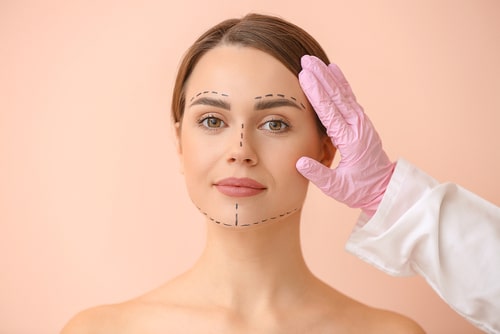 Plastic surgeon touching face of young woman