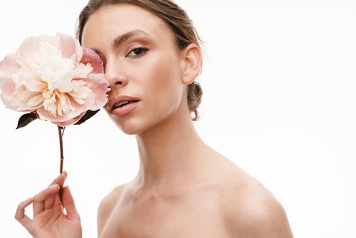 beautiful caucasian young shirtless woman holding peony flower