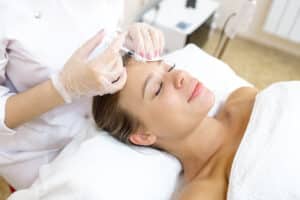 Woman laying down and receiving Botox injections in her forehead for wrinkle reduction