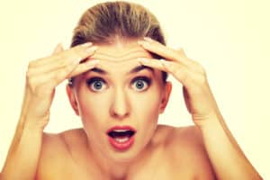 Woman with surprised look touching her forhead consider BOTOX or brow lift in Denver